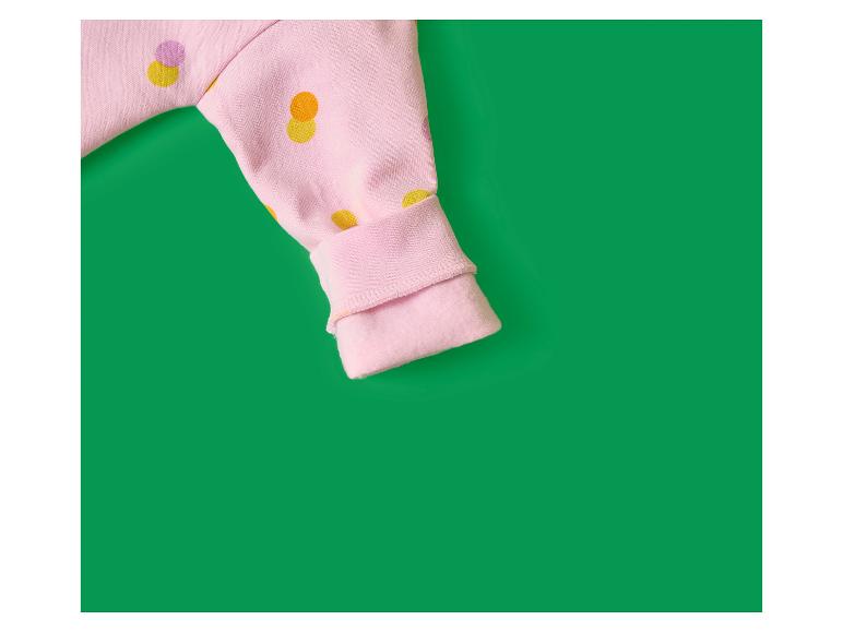 Roze mouw met kleurrijke stippen op een groene achtergrond.