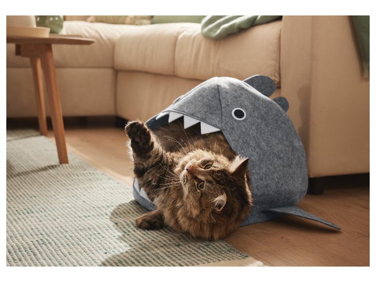 Een kat speelt in een grijs haaienvormig dierenbed.