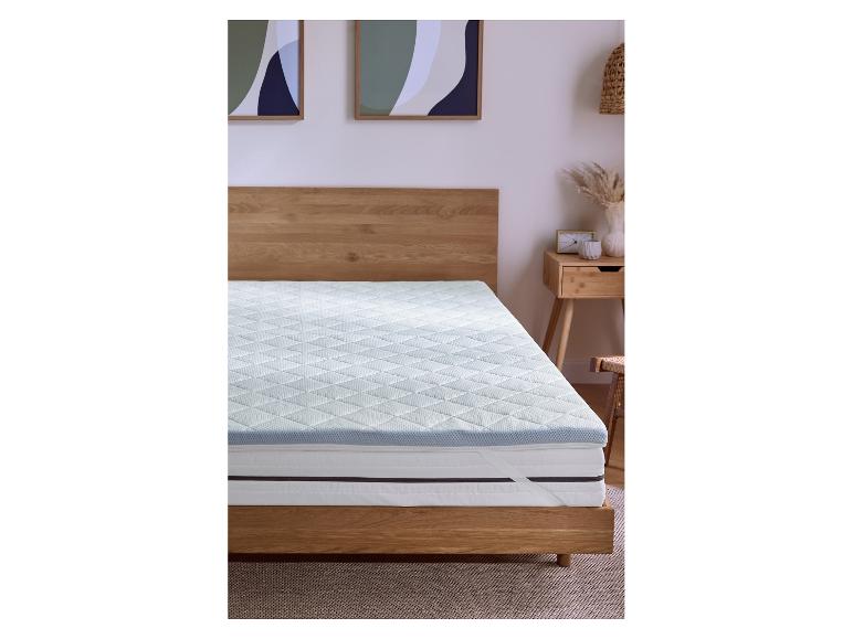 Matras met topper in slaapkamer met houten bed en nachtkastje.