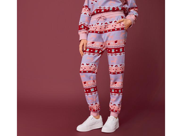 Vrouw draagt een joggingbroek met kerstprint en witte sneakers.