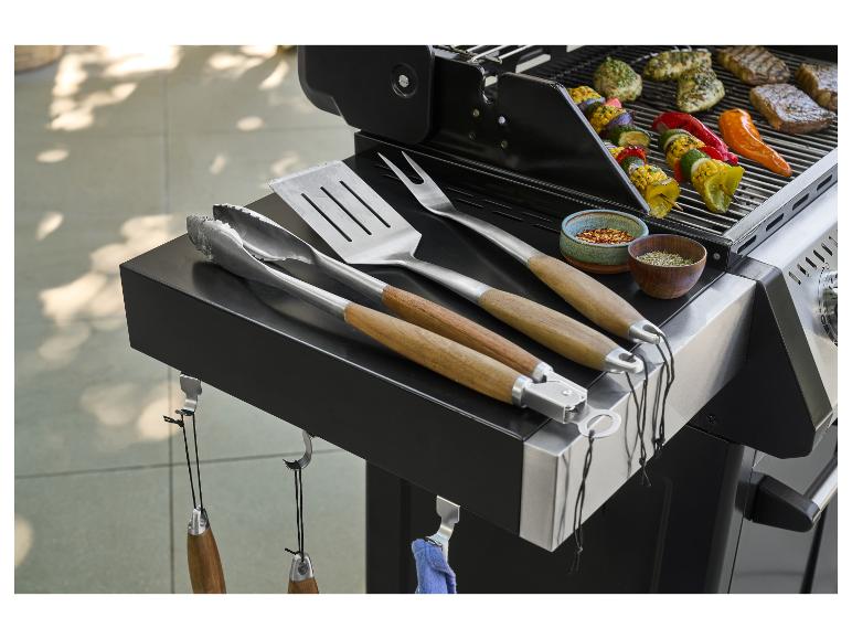 Barbecue met keukengerei, kruiden en gegrilde vlees- en groentespiesen.