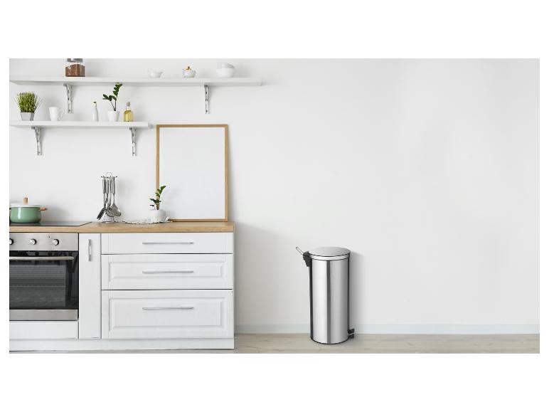 Moderne keuken met witte kasten, houten aanrechtblad en een roestvrijstalen prullenbak.