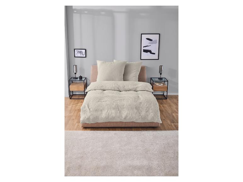 Crèmekleurig beddengoed op een bed met twee nachtkastjes.