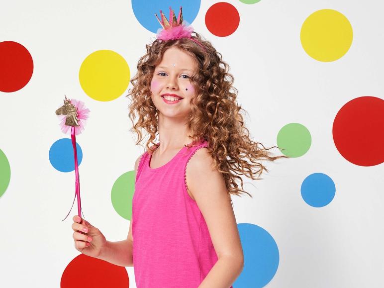 Een meisje met een roze top en een unicorn-toverstaf voor een achtergrond met gekleurde stippen.