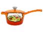 Oranje steelpan met deksel, met courgettenoedels, tomaten en pijnboompitten erin.