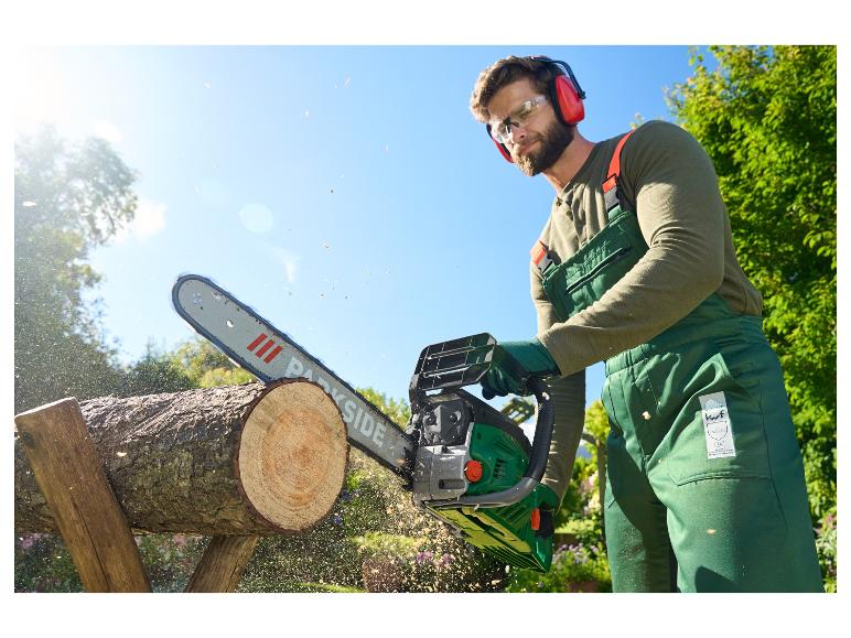 Een man gebruikt een Parkside kettingzaag om hout te zagen.