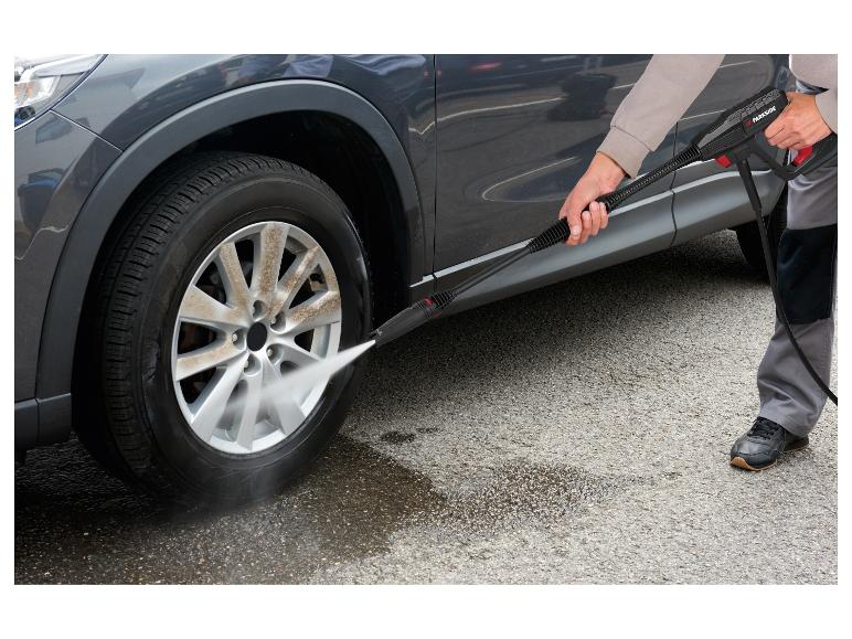 Man wast een vuile autowiel met een hogedrukreiniger.