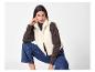 Vrouw in een crèmekleurig teddy fleecevest, bruine coltrui en blauwe jeans.