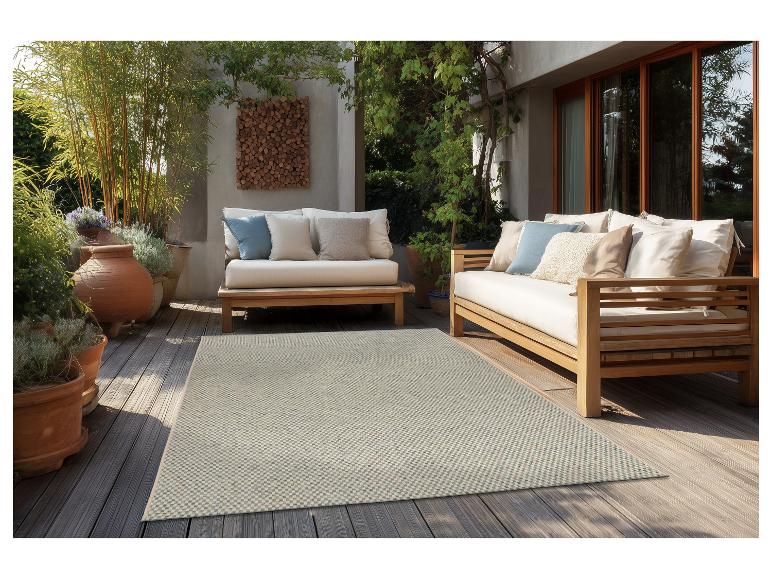 Terras met houten buitenmeubilair, lichte kussens en een patroonkleed.