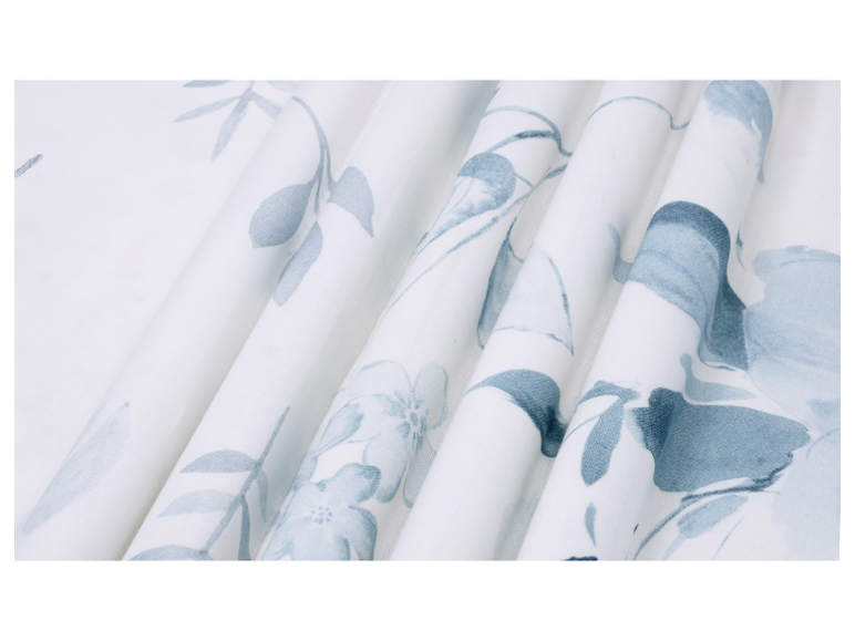 Witte stof met blauw bloemenpatroon, gevouwen in plooien.
