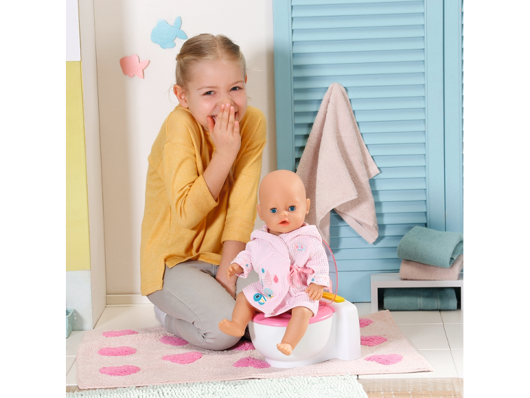 Lachend meisje met pop op een potje, in een badkameromgeving.