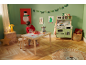 Een kind speelt met een houten speelgoedkeuken en tafelset in een kamer in kerstsfeer.