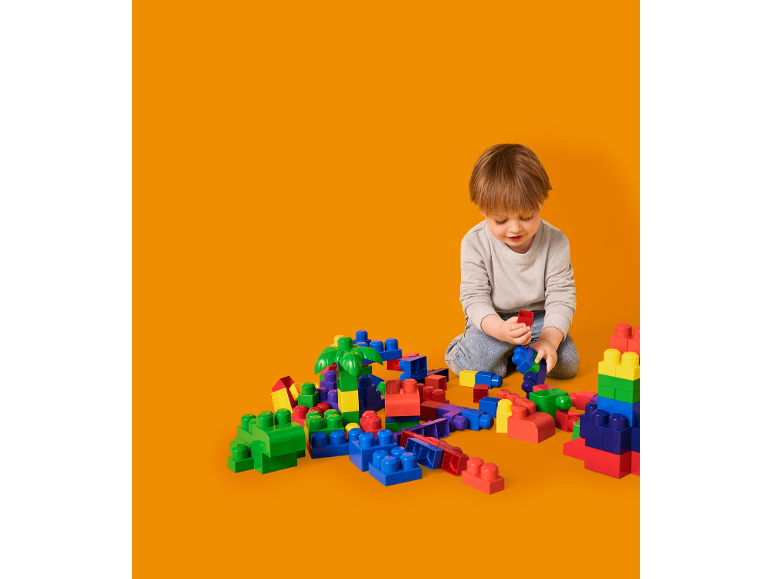 Peuter zittend op de grond spelend met kleurrijke bouwstenen.