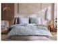 Slaapkamer met blauw bloemig beddengoed, houten lambrisering en schilderij.