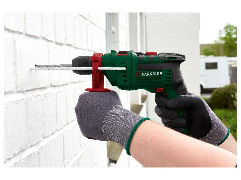 PARKSIDE klopboormachine boort in een witte muur, vastgehouden door gehandschoende handen.