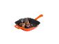 Oranje gietijzeren grillpan met twee steaks, uien en champignons