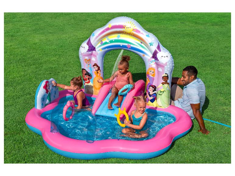 Kinderen spelen in een opblaasbaar prinsessenwaterpark met glijbaan en sproeiers op gras.
