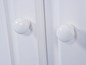 Twee witte knoppen op een witte kastdeur.