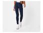 Een persoon draagt donkerblauwe skinny jeans, een bruine jas en witte sneakers.