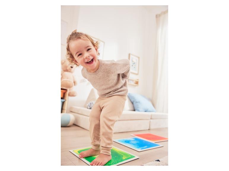 Blij kind speelt op kleurrijke vloeibare vloertegels.