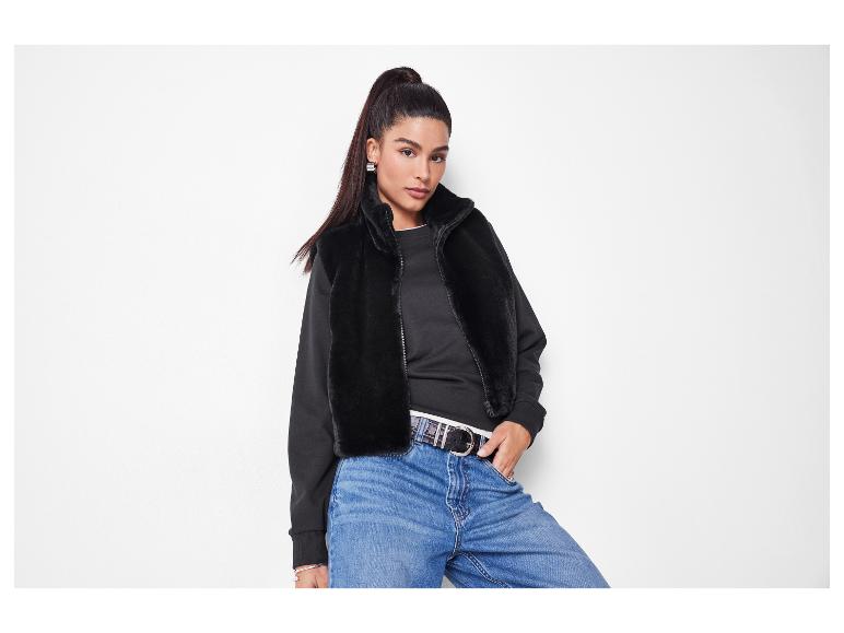 Vrouw in zwarte imitatiebontjas, zwarte top en blauwe jeans met riem