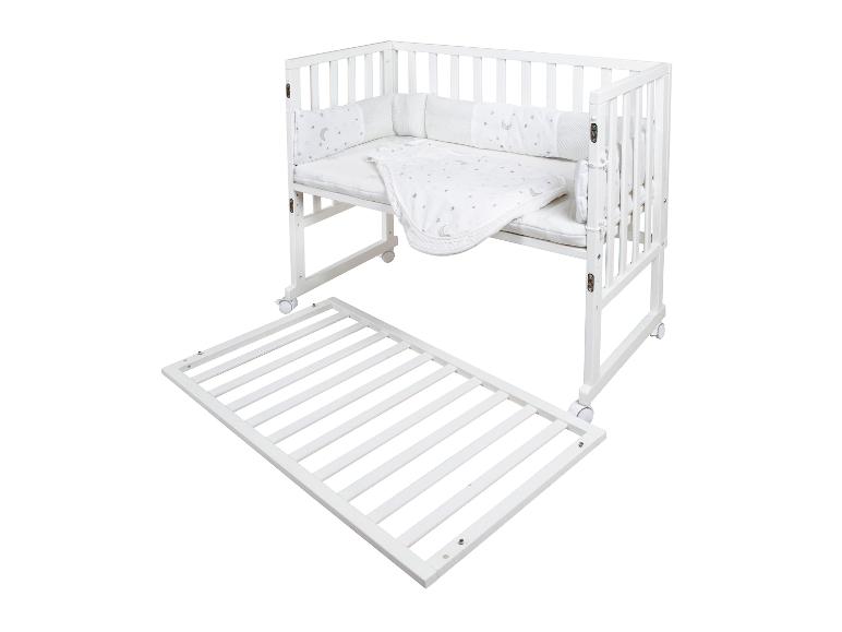 Wit babybedje met maan- en sterrenpatroon beddengoed, met een afneembare matrasbodem.