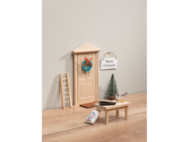 Miniatuur elfenhuisdeur met kerstversiering en bakaccessoires.