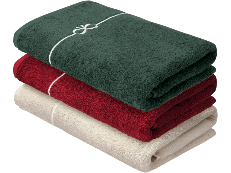 Stapel gevouwen handdoeken in donkergroen, rood en beige, de bovenste met een witte strik.
