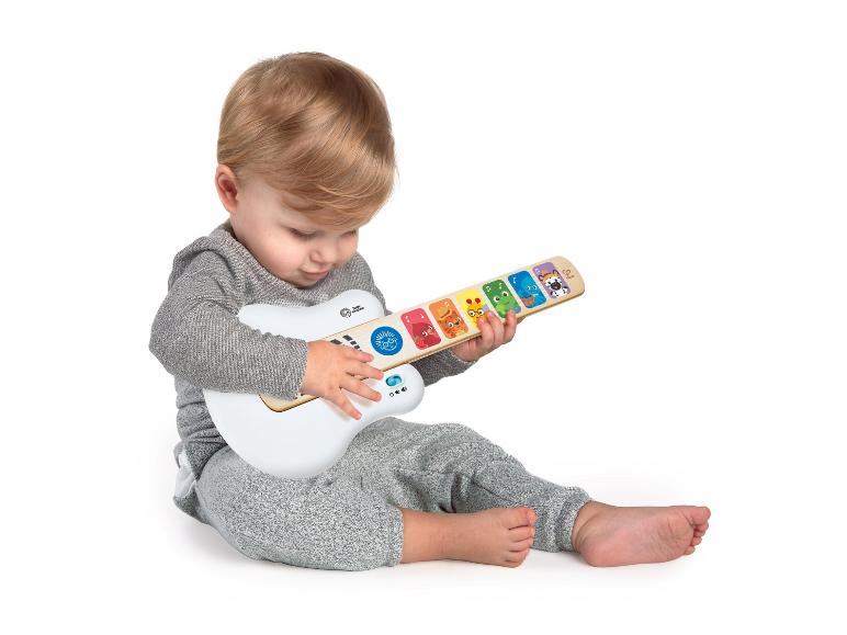 Peuter speelt met een witte en houten Baby Einstein speelgoedgitaar.