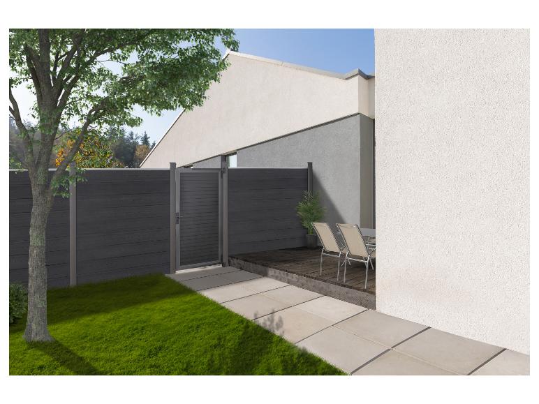 Moderne tuin met donkergrijze schutting en poort, houten vlonder, tuinmeubelen en een boom.