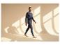 Man in donkerblauwe thermokleding, lachend, blootsvoets lopend in zonlicht.