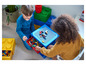 Twee kinderen spelen met LEGO-stenen op een LEGO-tafel en in LEGO-opbergdozen.