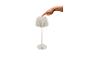 Witte tafellamp met geplooide kap en een hand die de aan/uit-knop indrukt.