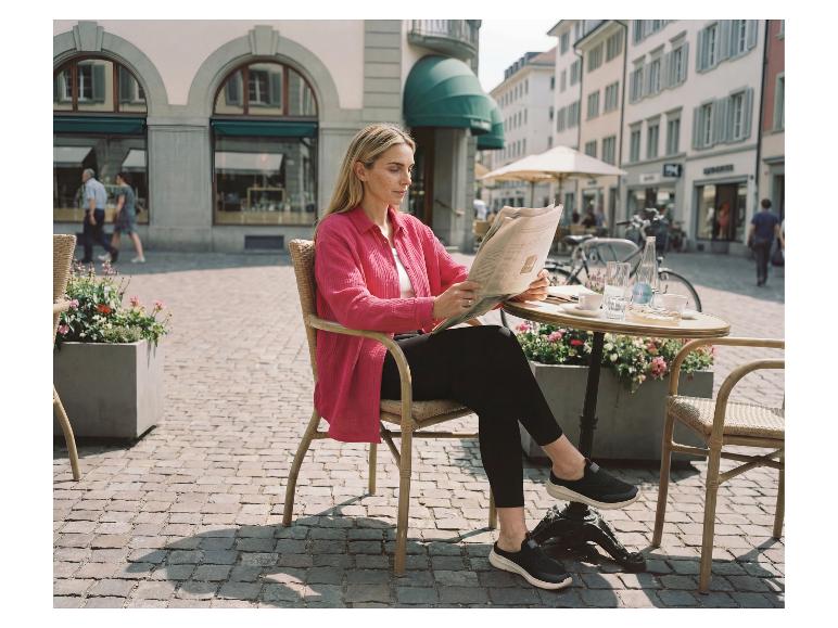 Vrouw in ESMARA® capri-legging zit op een terras en leest de krant.