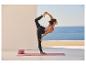 Vrouw in yogakleding doet de danserhouding op een yogamat met blokken.