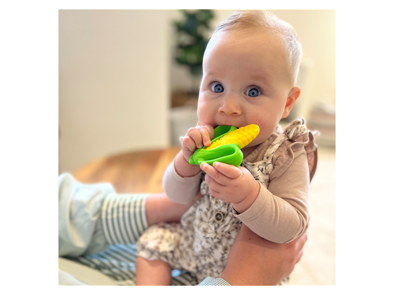 Baby met een maïs-vormig bijtring.