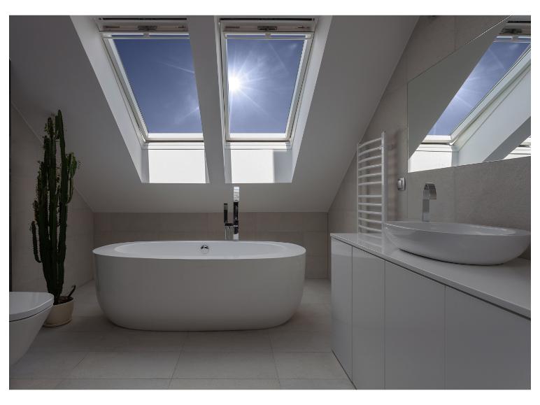 Moderne zolderbadkamer met vrijstaand bad, wastafel en dakramen.
