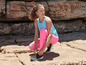 Een vrouw in roze leggings en een blauwe tanktop bindt haar sportschoenen.