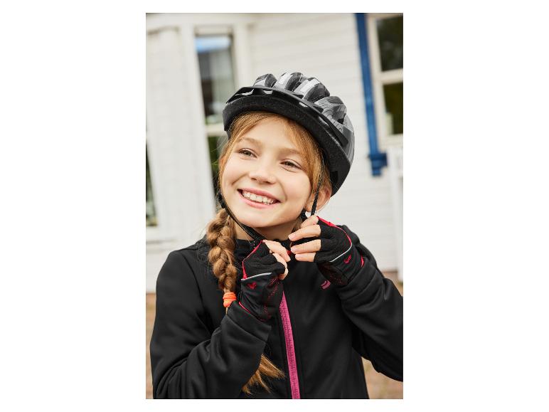 Meisje in zwarte jas en handschoenen, past fietshelm aan
