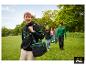 Man in zwarte hoodie met groene koeltas, wandelend met vrienden in een park.