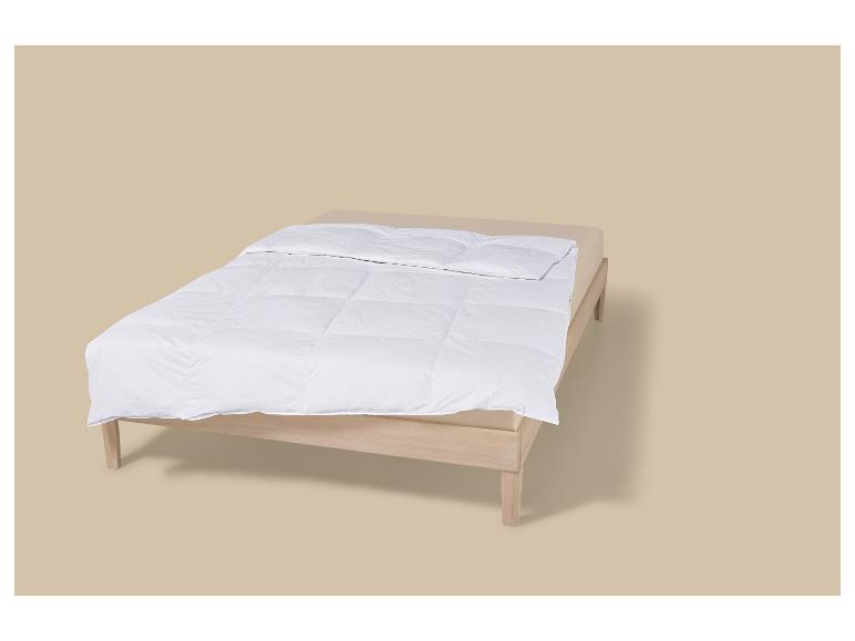 Bed met houten frame en wit dekbed op een beige achtergrond.
