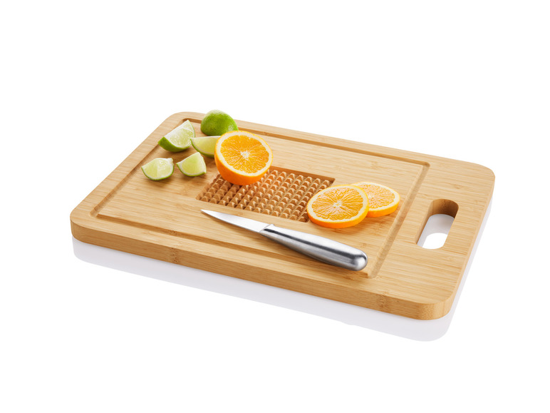 Een houten snijplank met oranje en limoenpartjes en een mes.
