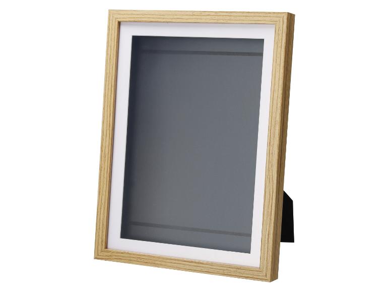 Licht houten fotolijst met wit passe-partout en grijze achtergrond, zijaanzicht.