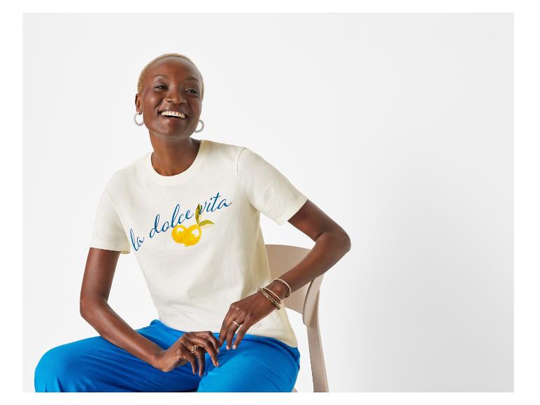 Crèmekleurige t-shirt met "La dolce vita" print en blauwe broek.