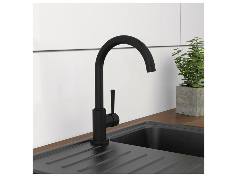 Een zwart keukenkraan boven een zwarte spoelbak.