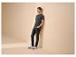 Man in een donkergrijs T-shirt met 'LIFE BEGINS' tekst, zwarte jeans en witte sneakers.