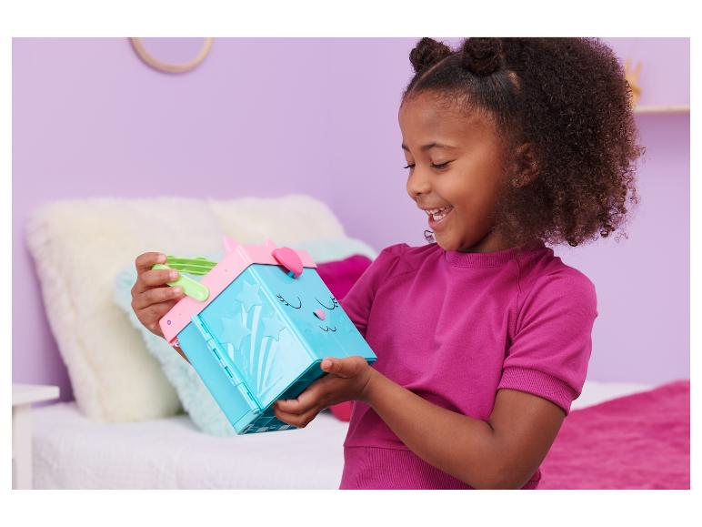 Blij meisje houdt een blauwe en roze speelgoeddoos met een kattengezicht vast.