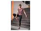 Vrouw in paarse en zwarte sportkleding doet yoga op een grijze mat.