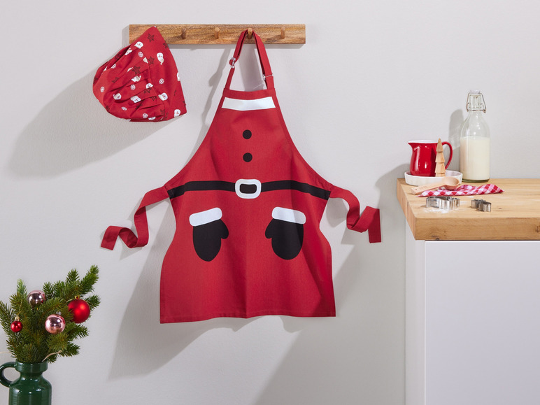 Een rode kerstman schort en muts, hangend aan een haak.