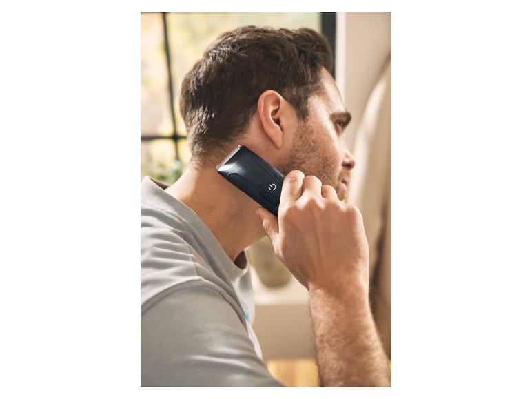 Man gebruikt een zwarte tondeuse om zijn nek te scheren.